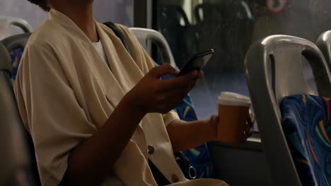 female commuter having coffee while using mobile phone in bus 4k