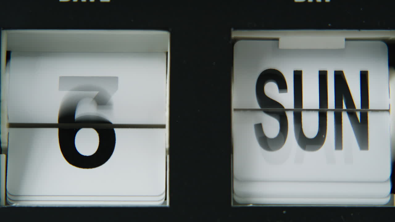 Closeup flip clock calendar switching panels with black digits. Macro view date