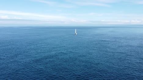 flying towards and around a small yacht as it slowly sails through a calm ocean