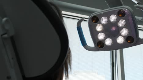 a dentist adjusts the lights above a patient before a dental exam