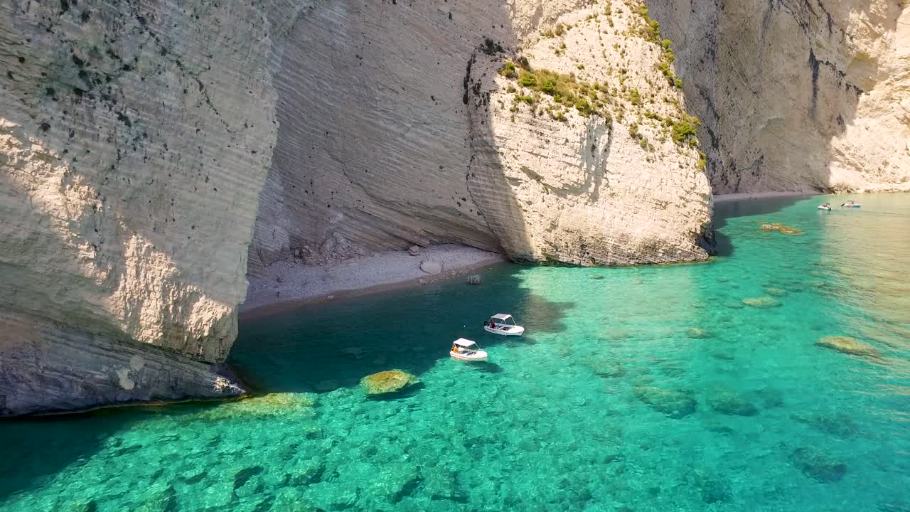 playa de oasis con barcos cerca de las cuevas de keri, zakynthos, aguas cristalinas y acantilados escarpados, día soleado, vista aérea