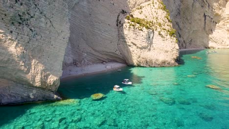 Playa-Oasis-Con-Barcos-Cerca-De-Las-Cuevas-De-Keri,-Zakynthos,-Aguas-Cristalinas-Y-Acantilados,-Día-Soleado,-Vista-Aérea.