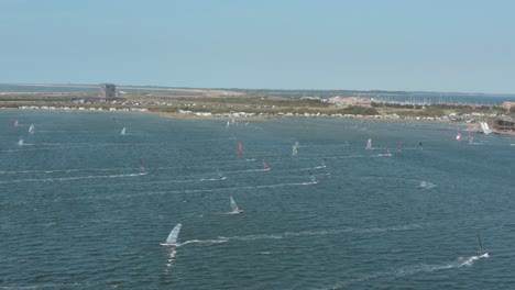 drone - aerial shot of many surfers on a blue, wavy and windy sea on a sunny day with white clouds on a island, zeeland, netherlands, 30p