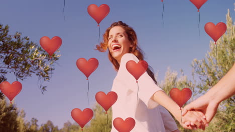 multiple heart balloons floating against couple holding hands and running