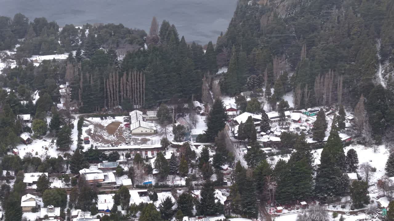 Wide snowy aerial landscape of residential suburban area with surrounding forest and mountains, Colonia Suiza, Bariloche, Argentina