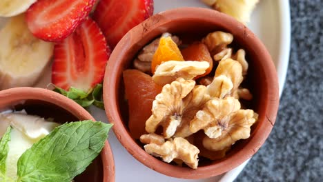 close-up of walnuts and dried apricots in a small clay bowl