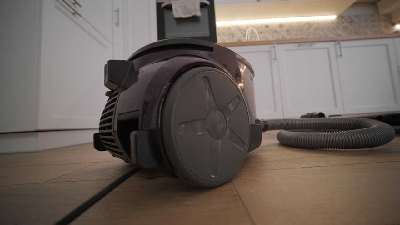 Vacuum Cleaner Running on Wooden Floor in a Modern Kitchen