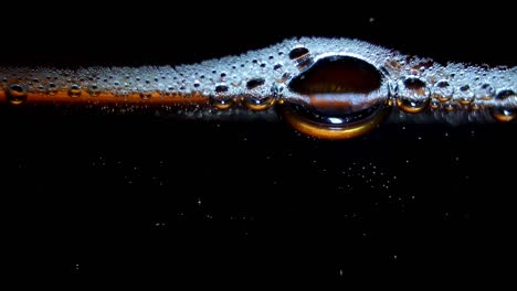 studio close up abstract macro shot with moving bubbles of co2 carbon dioxide fizzy beverage drink creating foam