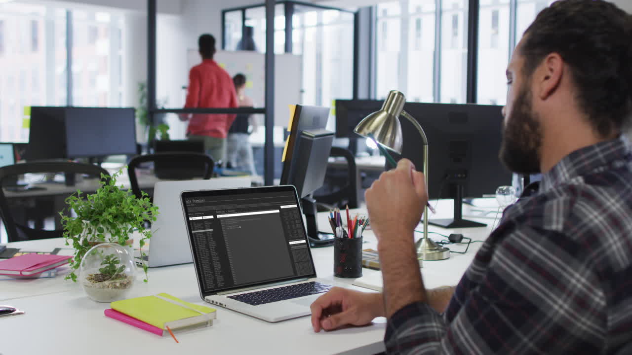 Caucasian man sitting at desk watching coding data processing on laptop screen