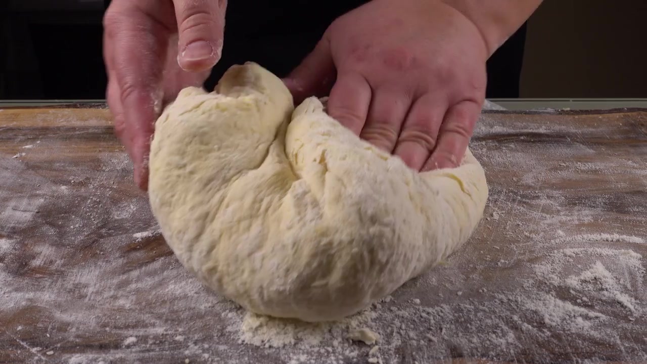 Impastare la pasta su un tagliere di legno con le mani