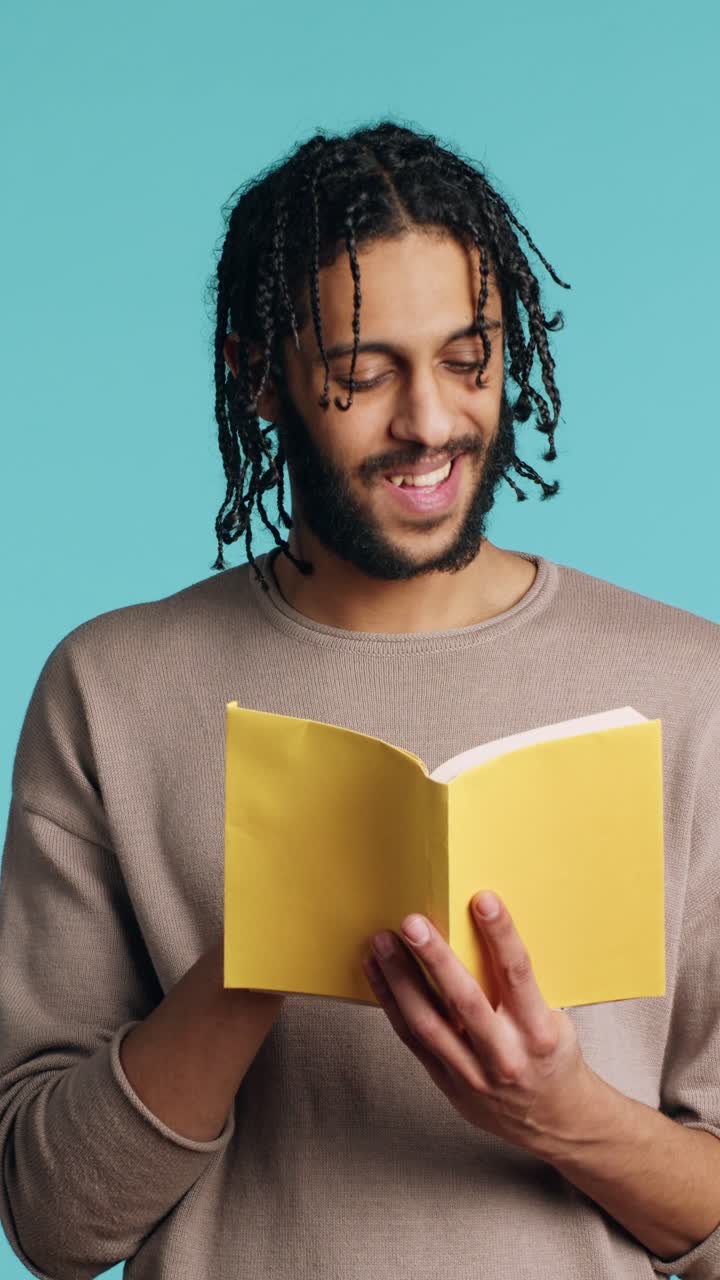 Vertical video Man reading newly released hardcover book from publisher, studio background