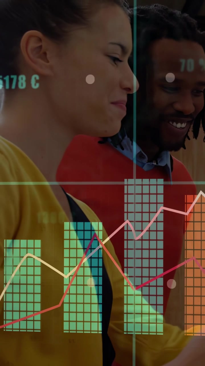 Two co-workers watching display updating as animated finance charts rise, analyzing sales trends