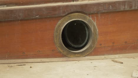 brass porthole window in traditional wooden sailboat