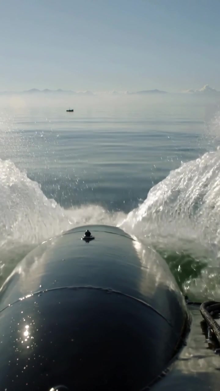 Vertical video: Surging bow tube after surge, creating twin sprays and settling into calm sea wake