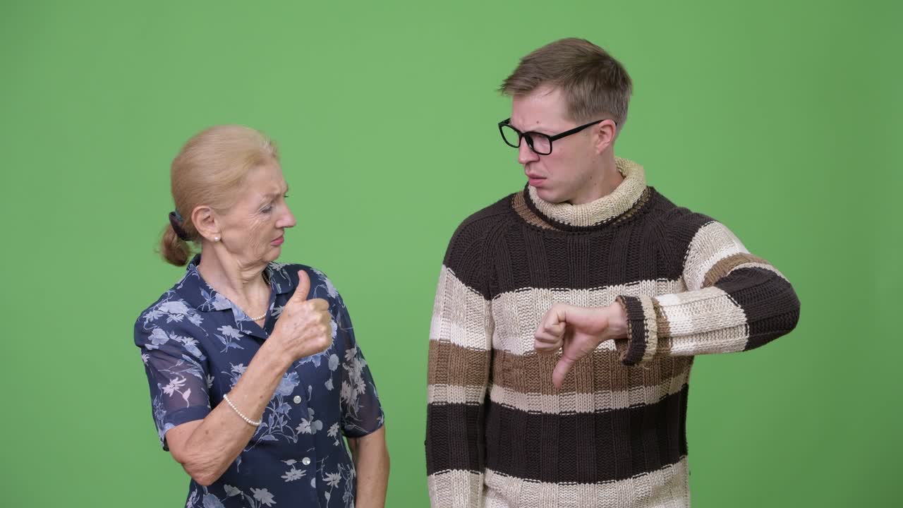 Happy grandmother giving thumbs up while upset grandson giving thumbs down