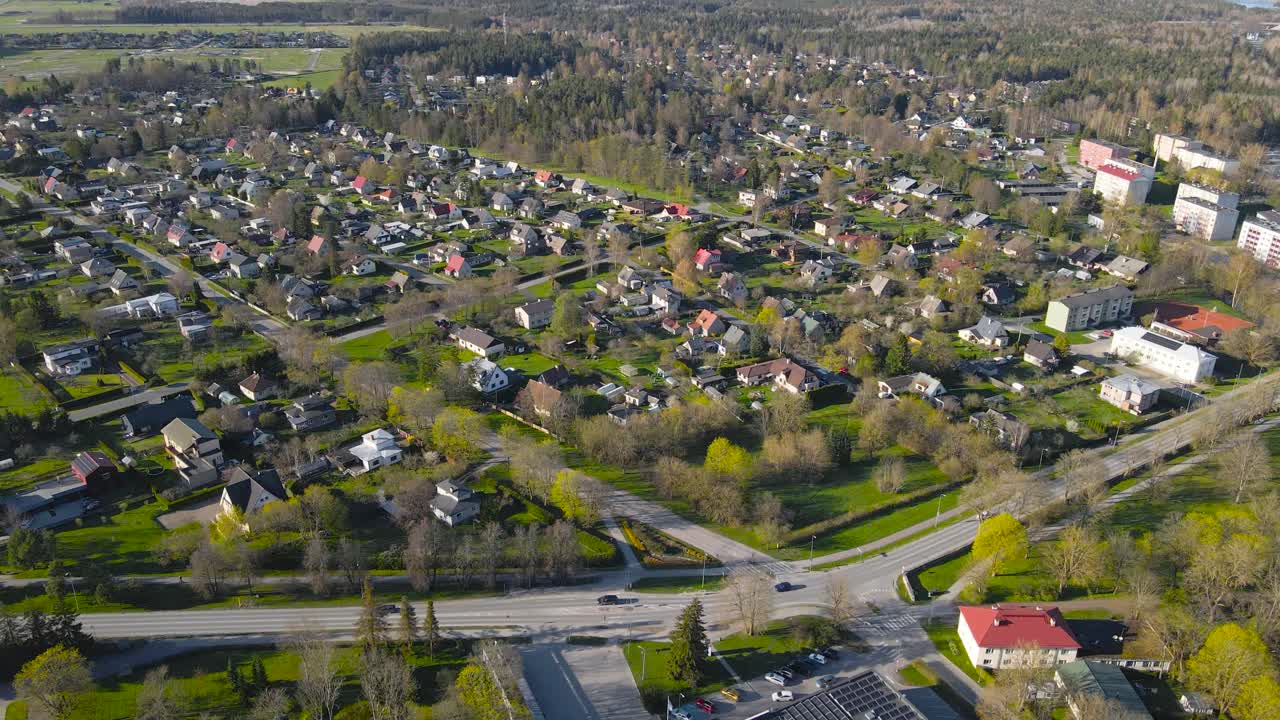 Gorgeous aerial drone footage panning and flying above Saku residential neighborhood area during a sunny day while small houses, rooftops and green yards and gardens are visible, cars driving on roads