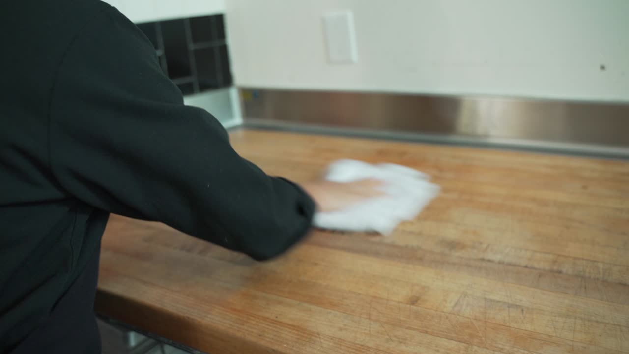 Shows a red bucket full of sanitizing solution and it is used to clean the cooking area of chefs and lead cooks at a restaurant.