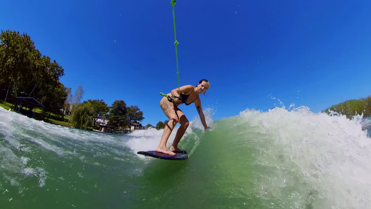 Wakesurfer balancing on the wake, boat churning waves across calm lake
