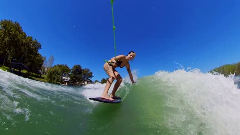 wakesurfer balancing on the wake, boat churning waves across calm lake