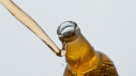 apertura de la botella de ipa de vidrio de primer plano. la cerveza sin filtrar salpicando el frasco condensador