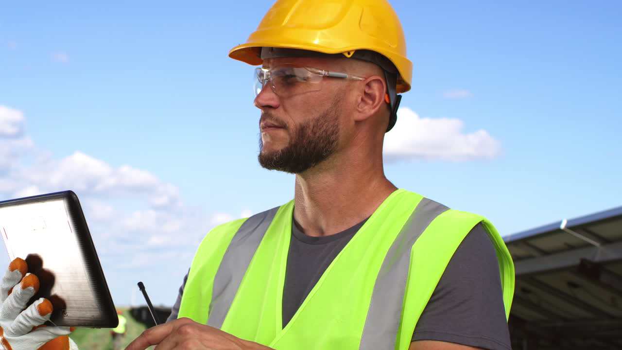 trabajador de la construcción inspeccionando paneles solares con una tableta