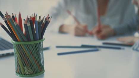 lápices de color en primer plano. niña haciendo la tarea con su madre.