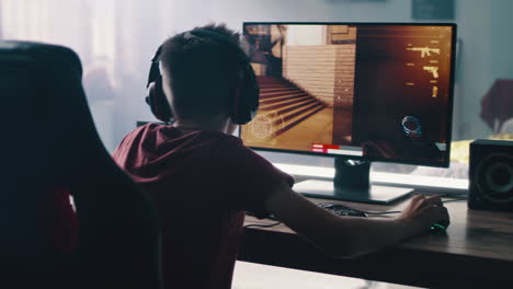 teenage boy playing a first-person shooter video game on a computer.