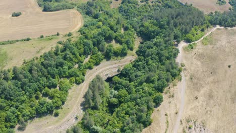 Overhead-drone-shot-above-the-natural-rock-arch-know-as-Gods-Bridge,-surrounded-by-trees-at-it-entrance,-located-near-Vratsa,-in-Bulgaria