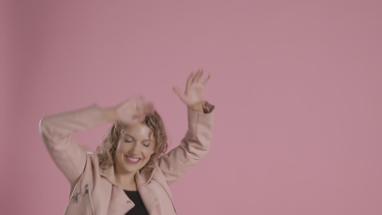 foto de estudio de una joven que se divierte bailando contra un fondo rosa 4