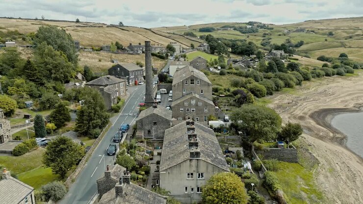 Aerial video footage of a rural industrial village with old mill and chimney stack