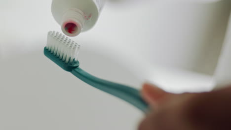 les mains de dentifrice sur la brosse à dents