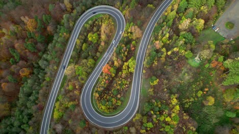 aerial view of a winding road in a yellow orange and green autumn forest in the mountains of bieszczady in poland