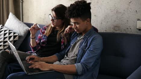 Young-happy-couple-of-two-hipsters-ordering-food-online,-using-laptop