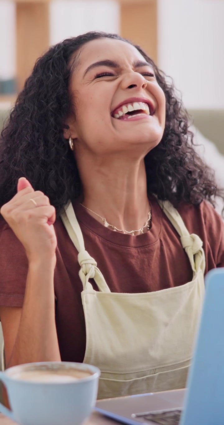 Giovane donna entusiasta che festeggia un successo mentre usa il laptop a casa