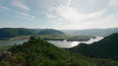 hombre en la cima de la cresta de la montaña, avión no tripulado rápido fpv, disparo aéreo con velocidad, rey del mundo pose, escalador de montaña, persona en la cima de la colina, valle del río danubio panorama del paisaje, volando alrededor volando rápido