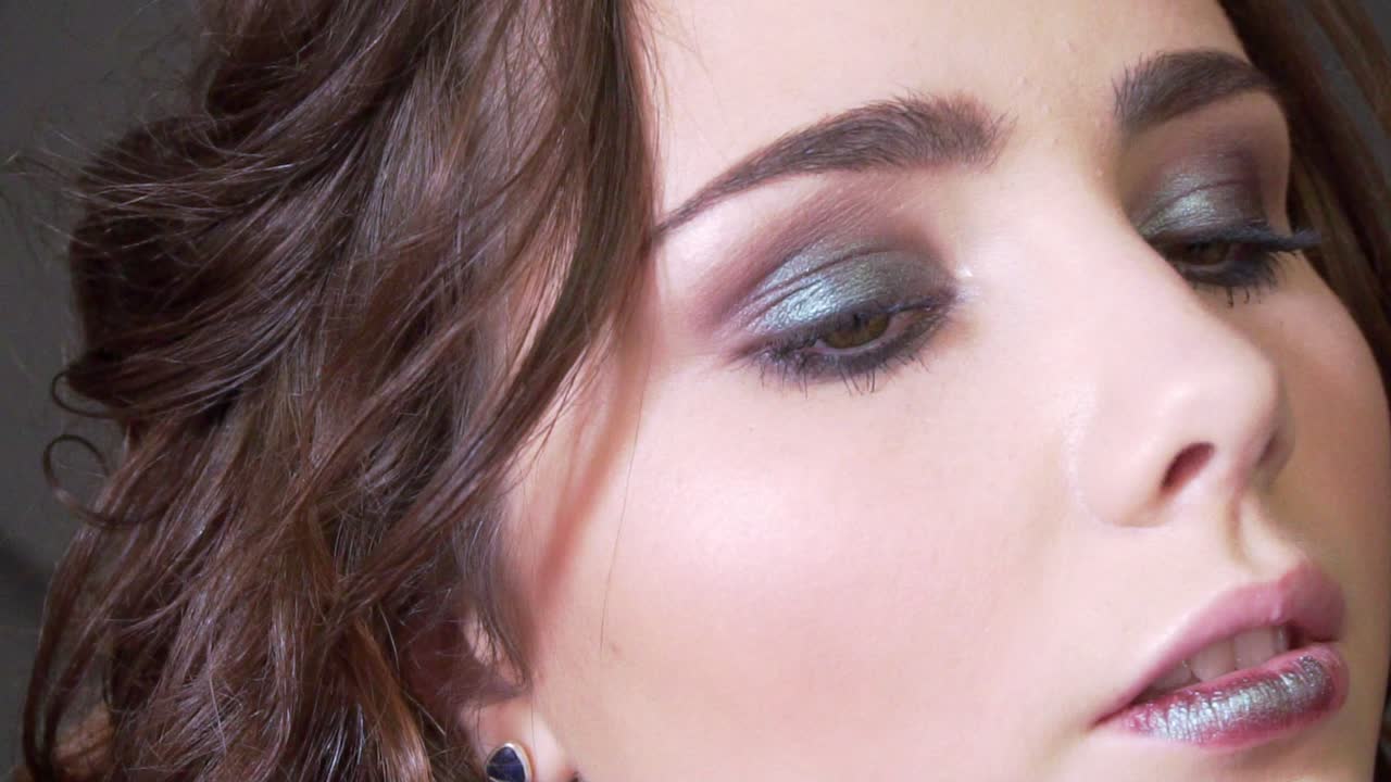 un estilista haciendo maquillaje mujer hermosa en el estudio con peinado ondulado