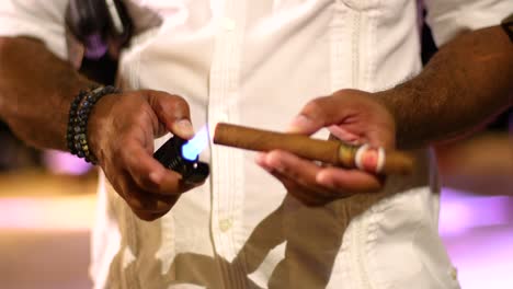 cerca de un hombre caribeño sosteniendo y encendiendo un cigarro con un encendedor.