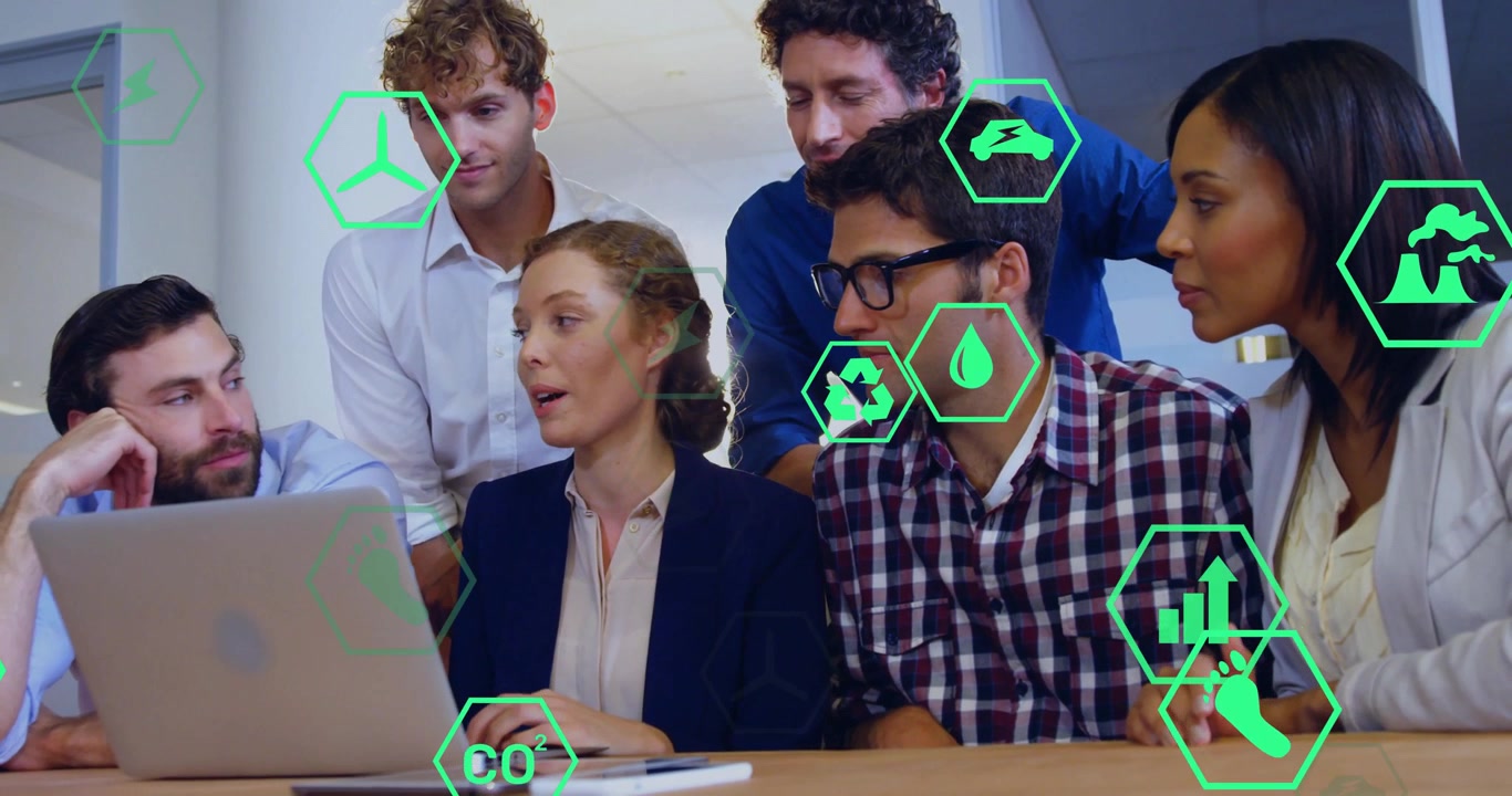 Professionisti aziendali che collaborano attorno a un laptop in un hub, mostrando icone di sostenibilità fluttuanti.