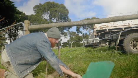 Ein-Schuss,-Der-über-Ackerland-In-Victoria,-Australien,-Schwenkt,-Während-Ein-Mann-Werkzeuge-Verwendet,-Um-Pfähle-In-Den-Boden-Zu-Stecken,-Während-Er-Bäume-Pflanzt