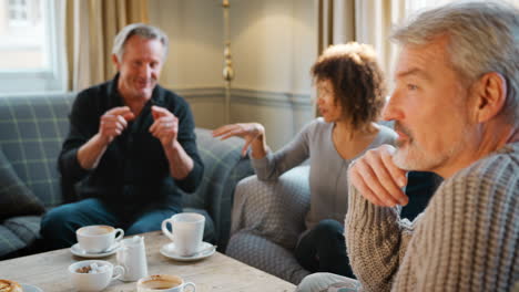 grupo de amigos de mediana edad reunidos alrededor de una mesa en una cafetería
