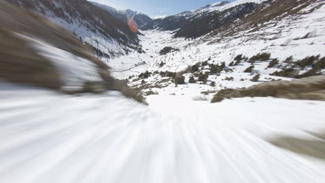 racing drone descending towards snowy valley, pyrenees