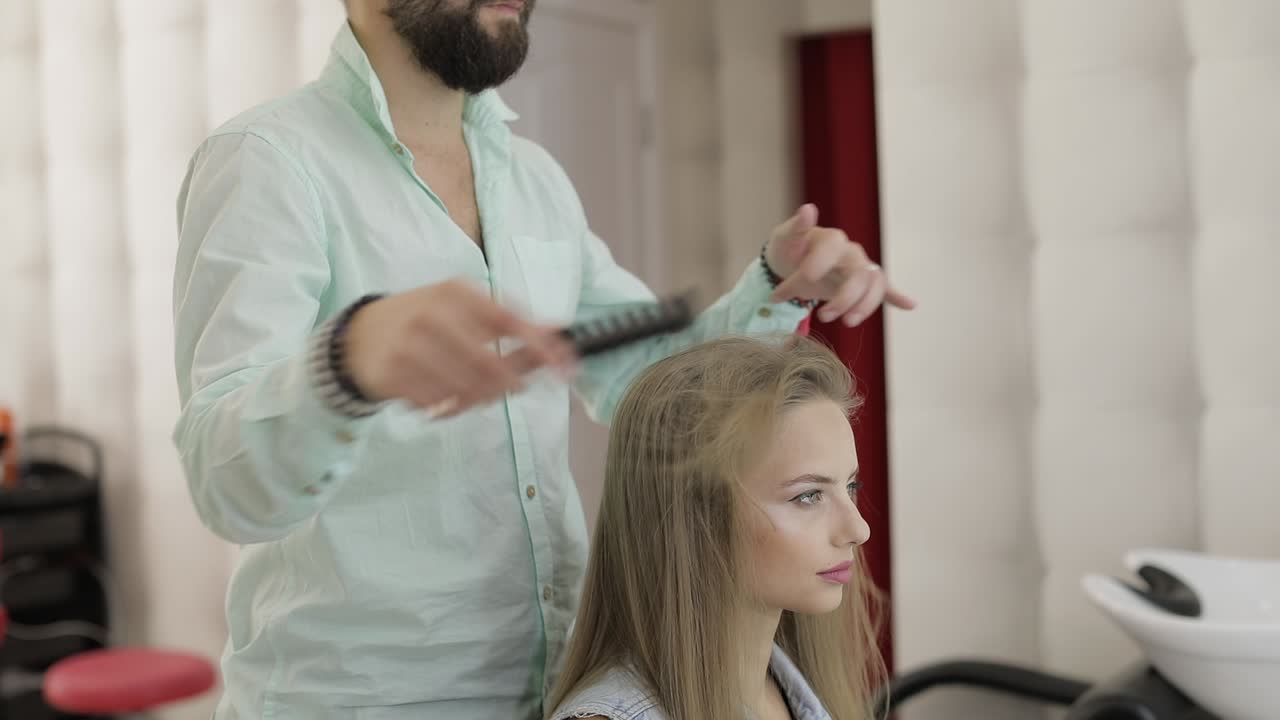 Profesjonell frisør styler og grer modellens hår. Lager volumfrisyre.