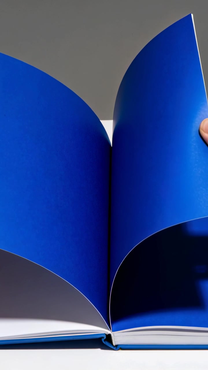 Video verticale: Mani nude che entrano e sfogliano pagine su un tavolo da studio, rivelando pagine di un libro blu scuro.