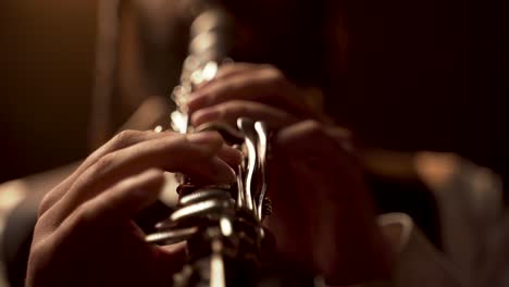 fingers player on clarinet, in a dark room