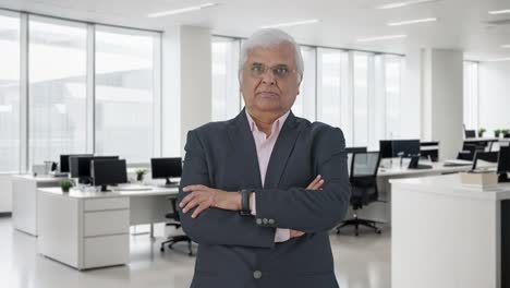 Indian-senior-businessman-standing-crossed-hands