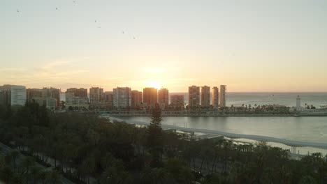 epic sunrise behind the skyscraper buildings on the harbor of malaga early in the morning