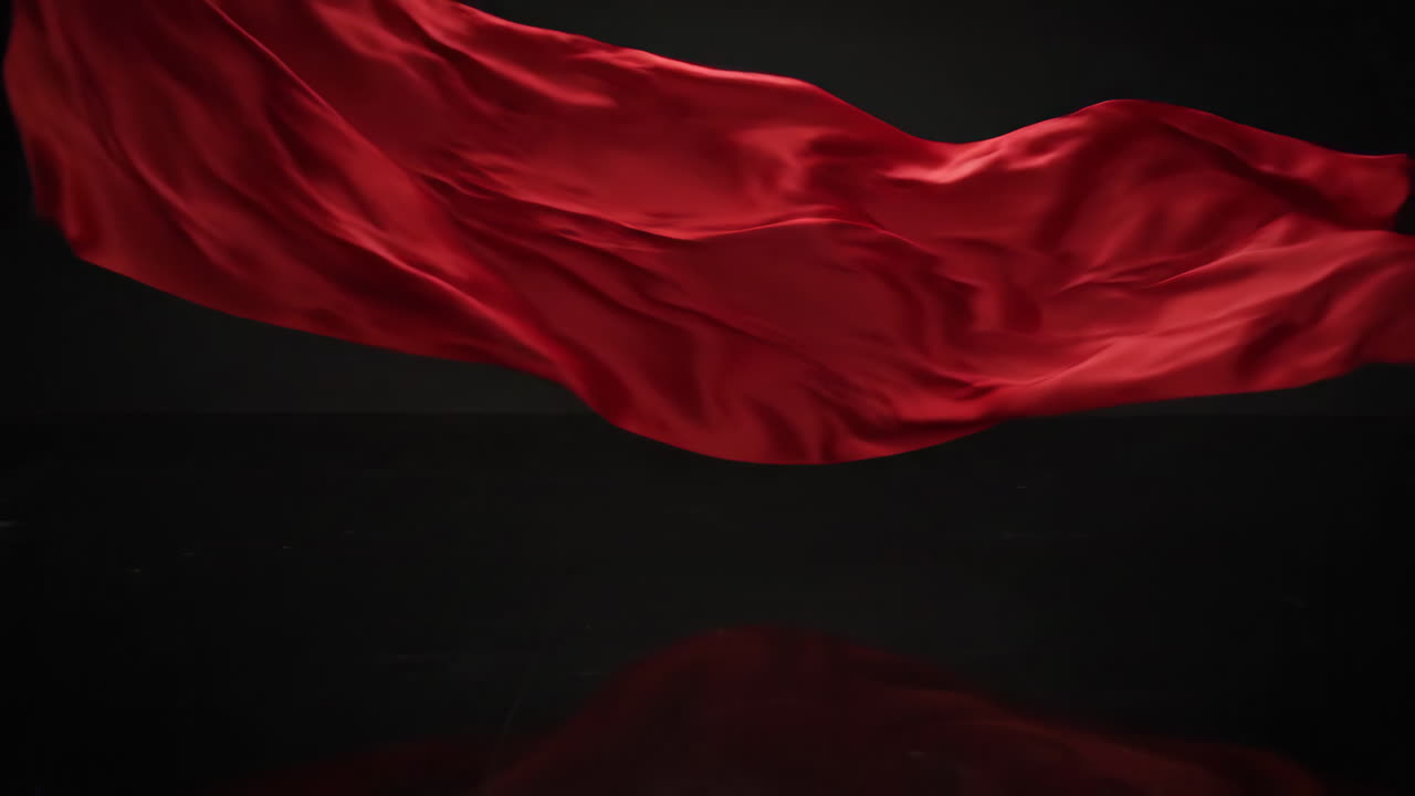 Red Fabric Flowing on Black Reflective Surface
