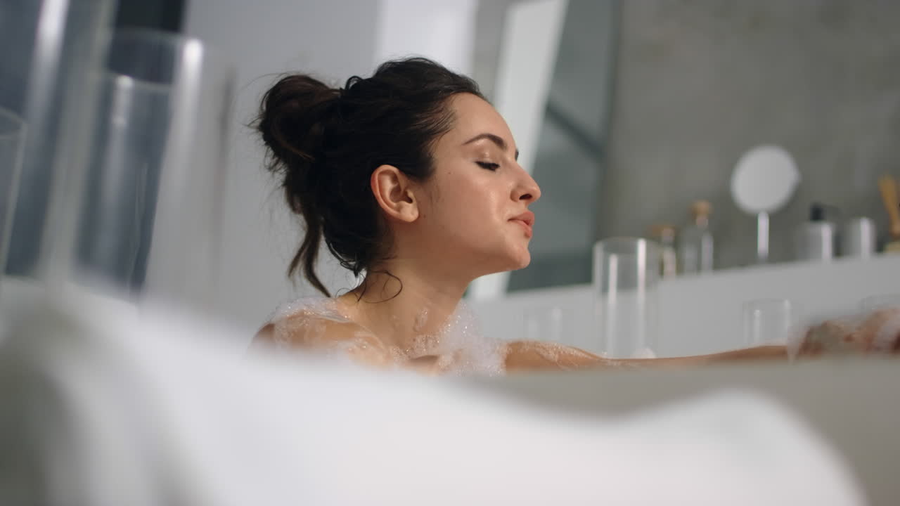 Caucasian woman washing skin in bath
