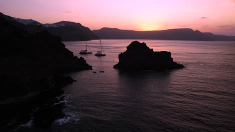 purple sunset above santorini island greece and boats in aegean sea, aerial view