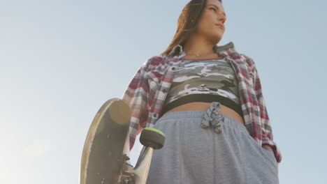 midsection of caucasian woman holding skateboard at a skatepark